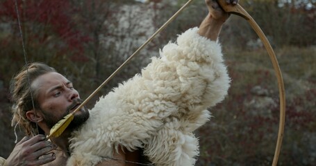 A skilled hunter in furs draws a bow, reflecting a connection to nature and archery