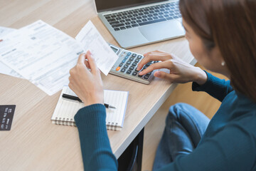 Stressed asian young business woman, employee using calculator to calculate expenses of monthly,...