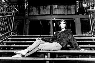Obraz premium A woman sits on stairs, dressed in black and white, with a calm and serene expression on her face.