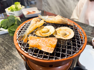 Asian woman enjoy eating grilling beef and seafood barbecue.