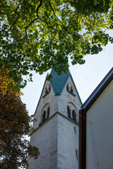 Historic church tower framed by tree branches in Mayrhofen, Austria during early morning light