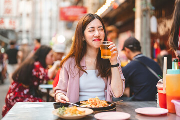 Young adult traveler woman enjoy eating street food spicy thai tasty menu travel at chinatown Yaowarat, Bangkok, Thailand