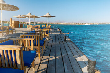 Obraz premium Wooden pier on sea stretching into distance beyond horizon on sunny summer day. Vacation and Travel Concept.