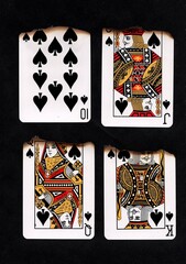 Partially burnt playing cards in the suit of spades.