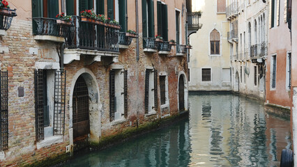 Explore the serene canals of Venice with charming buildings and vibrant flower boxes along the waterway