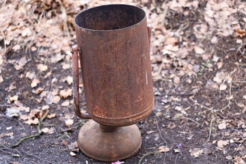 Naklejka premium A old and rusty metal pot sitting on the surface of the earth, surrounded by natural terrain.