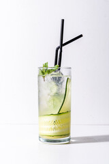 A tall glass holds a refreshing cucumber mint beverage surrounded by ice cubes