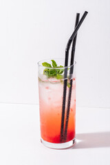 A vibrant drink features red and pink layers, garnished with mint and served chilled