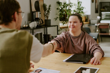 Over shoulder view of unrecognizable job interviewer shaking hands with excellent candidate with down syndrome © AnnaStills