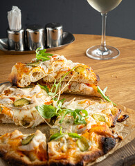 Freshly baked Italian pizza topped with vibrant vegetables and served alongside a glass of wine
