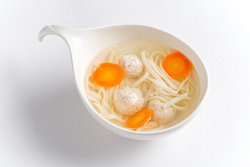 A comforting noodle soup filled with tender meatballs and vibrant carrot slices, inviting warmth