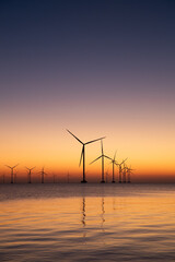 Windturbines in the water during sunset. Producing alternative energy.