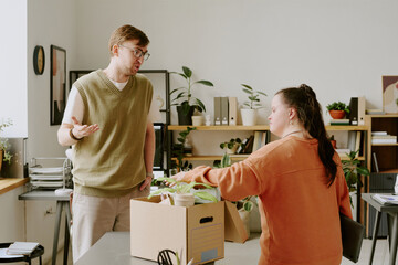 Wide shot of friendly male office worker chatting with new female coworker with down syndrome...