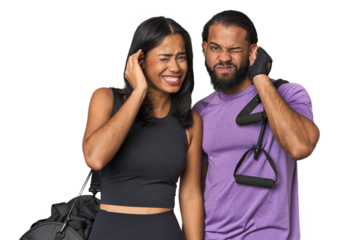 Young Latino couple ready for gym training covering ears with hands.
