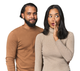 Young Latino couple in studio is saying a secret hot braking news and looking aside