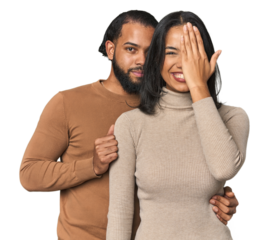 Young Latino couple in studio having fun covering half of face with palm.