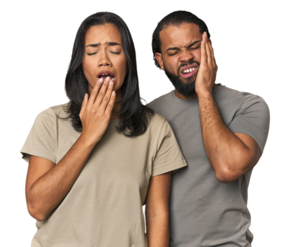 Young Latino couple in studio yawning showing a tired gesture covering mouth with hand.