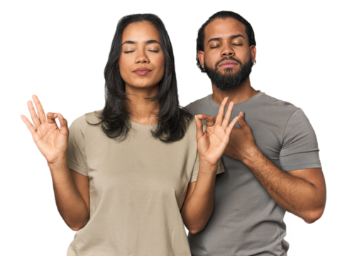 Young Latino couple in studio relaxes after hard working day, she is performing yoga.