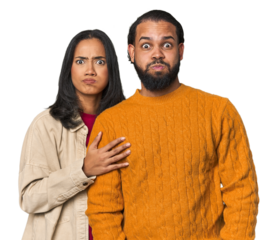 Young Latino couple in studio blows cheeks, has tired expression. Facial expression concept.