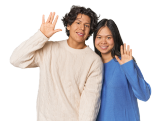 Young interracial couple in studio smiling cheerful showing number five with fingers.