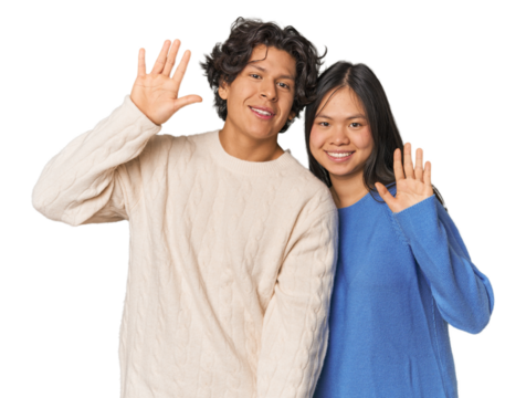 Young interracial couple in studio smiling cheerful showing number five with fingers.