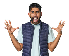 Young Hispanic man isolated screaming to the sky, looking up, frustrated.