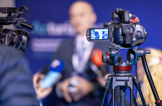 Blurry speaker in front of television video cameras giving a news conference or media interview