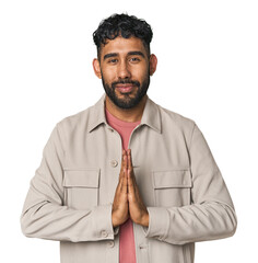 Young Hispanic man isolated praying, showing devotion, religious person looking for divine...