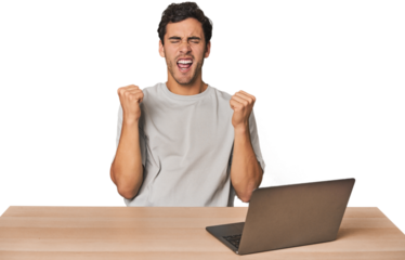 Hispanic young man working on laptop cheering carefree and excited. Victory concept.