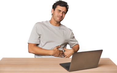 Hispanic young man working on laptop suffering a back pain.