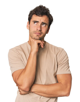Young Hispanic man in studio thinking and looking up, being reflective, contemplating, having a fantasy.