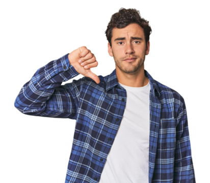 Young Hispanic man in studio showing a dislike gesture, thumbs down. Disagreement concept.