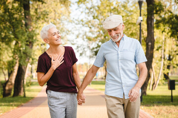 Romantic mature man and woman drinking coffee to go walking together on summer park. Happy loving...