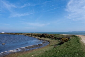 footpath along the Solent Way between Lymington and Keyhaven on a sunny spring day with blue sky in the background