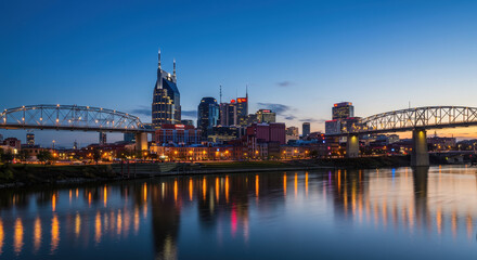 Naklejka premium Nashville Skyline at Dusk: River Reflections, City Lights, and Bridges of Tennessee.