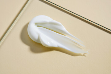 A smear of white cream on a beige background.