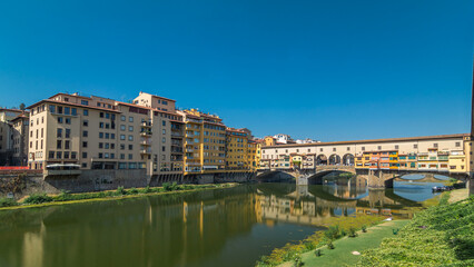 Obraz premium The Ponte Vecchio on a sunny day timelapse hyperlapse, a medieval stone segmental arch bridge over the Arno River, in Florence, Italy