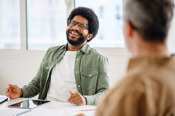 A confident African American businessman in glasses, relaxed and smiling during an office...