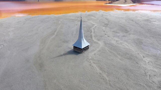 Mining toxic mud residuals in decanting lake choked a church aerial slow motion view