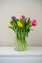 A beautiful arrangement of colorful tulips displayed in a clear vase placed on a white table