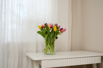 A beautiful arrangement of colorful tulips displayed in a clear vase placed on a white table