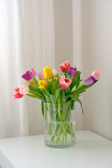 A beautiful arrangement of colorful tulips displayed in a clear vase placed on a white table