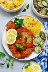 Traditional Viennese schnitzel on a plate with cucumber and potato salad.selective focus