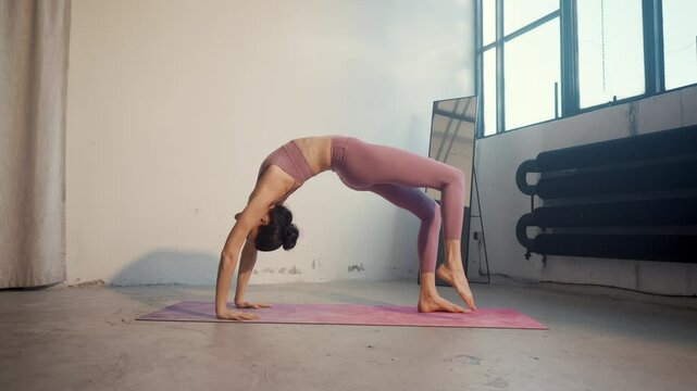A woman practices a graceful backbend in a serene yoga studio, enhancing mindfulness
