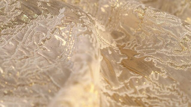 Golden natural brocade fabric with floral patterns rotate in circle. Textile material tissue cloth. Texture fabric close up. Fabric background