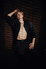 handsome man lies on the floor with an open shirt, revealing his six-pack, while looking up in thought, contemplating love, seduction, and sexy thoughts