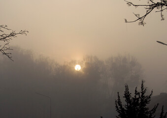 Sun disk becomes visible through fog.