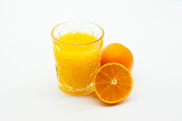 A glass of orange juice is next to an orange