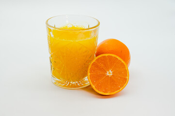A glass of orange juice is next to an orange