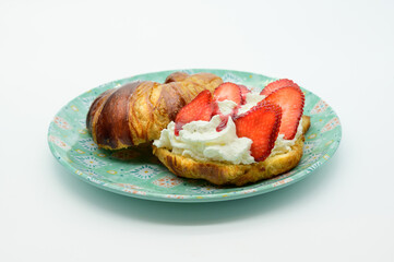 A croissant with strawberry jam and whipped cream on a blue plate